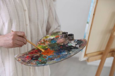 Ressamın stüdyosundaki resim sehpasında boyaları karıştıran adam, yakın plan.