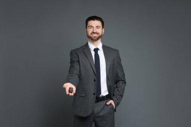 Gri arka planda araba anahtarı olan neşeli bir satıcı.