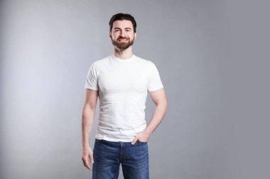 Açık gri arka planda beyaz tişört giyen bir adam. Tasarım için model