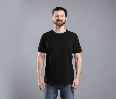 Açık gri arka planda siyah tişört giyen bir adam. Tasarım için model