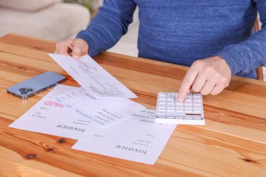 Faturaları ödüyorum. Hesap makineli adam, akıllı telefon ve faturalar kapalı masa, yakın çekim