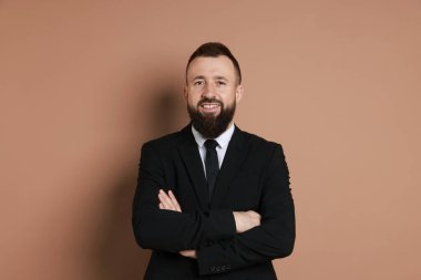 Kahverengi arka planda takım elbiseli yakışıklı sakallı adam.
