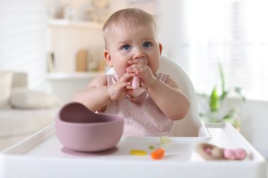 Evde kaşıkla yemek yiyen şirin bir bebek.