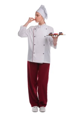 Üniformalı mutlu pastacı beyaz arka planda lezzetli ekinler tutuyor.