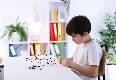 Çocuk içeride masa başında DNA yapısı modeli yapıyor. Metin için boşluk