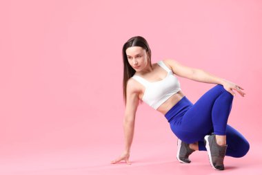 Spor kıyafetli kadın pembe arka planda poz veriyor, metin için boşluk var.