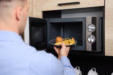 Yemek tabağını mikrodalgaya koyan adam, yakın plan.