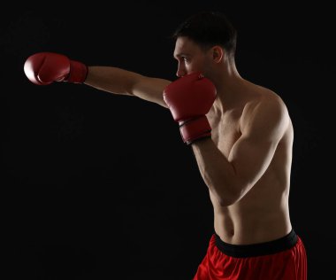 Siyah arka planda dövüşen boks eldivenli adam.