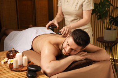 Adam spa salonunda taşlarla masaj yaptırıyor.