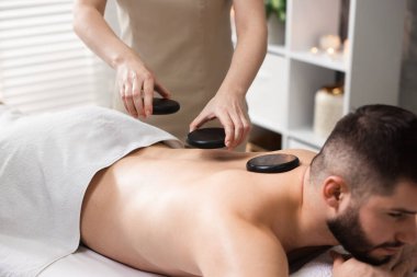 Adam spa salonunda taşlarla masaj yaptırıyor.