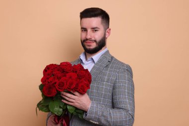 Bej arka planda kırmızı gül buketi olan adam.
