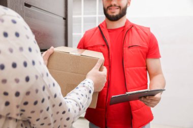 Elinde dosya olan kurye içerideki alıcıya paket veriyor, yakın plan.