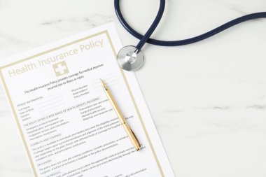 Sağlık sigortası poliçesi, steteskop ve kalem beyaz mermer masa, düz yatak. Metin için boşluk