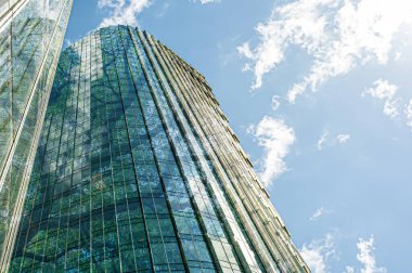 Modern gökdelenler ve masmavi gökyüzüne karşı yemyeşil ağaçlar, çift pozlama. Düşük açı görünümü