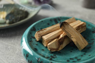 Yanan palo santo çubuğu ve değerli taş açık gri masada, yakın plan.
