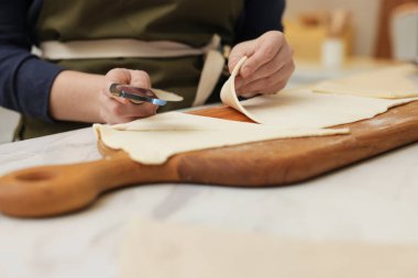 Işık masasında hamuru kesen kadın, yakın plan. Kruvasan yapıyorum.