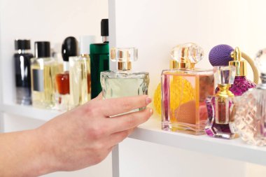 Kadın mağazadan bir şişe parfüm alıyor, yakın plan.