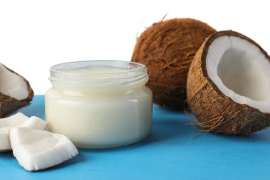 Açık mavi ahşap masada beyaz arka planda hindistan cevizi ve pişirme yağı