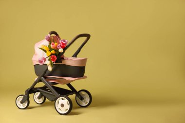 Şık bebek arabası ve zeytin zemininde laleler, mesaj için yer. Çocuk oyuncağı.