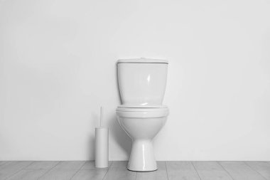 Toilet and brush on floor near white wall