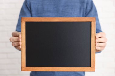 Kapalı alanda boş küçük tahta tutan adam, yakın plan.