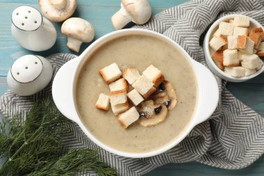 Lezzetli mantar kremalı çorba, kızarmış ekmek ve malzemeler mavi masada.