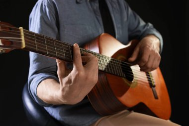 Siyah arka planda gitar çalan adam, ele odaklan.