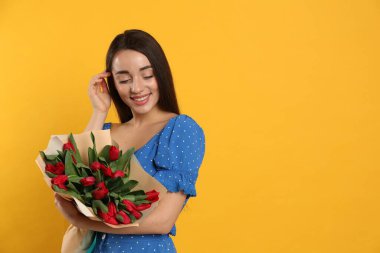 Sarı arka planda kırmızı lale çiçekli mutlu kadın, mesaj için yer var. 8 Mart kutlamaları