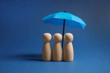 Mavi arka planda şemsiye altında insan figürleri. Sigorta konsepti