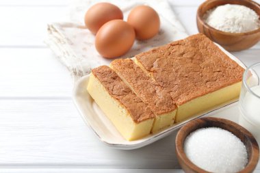 Tasty Japanese Castella sponge cake and ingredients on white wooden table