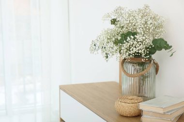 Vazoda okaliptüs dalları ve evde klozet üzerine kitaplar olan güzel çikila çiçekleri. Metin için boşluk