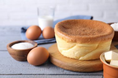 Tasty Japanese Castella sponge cake and ingredients on grey wooden table, closeup