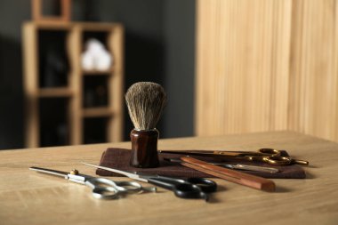 Berber dükkanında, açık ahşap masanın üzerinde birçok farklı berber aleti var.