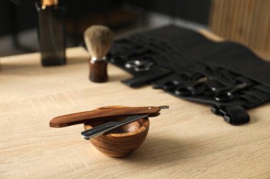 Berber dükkanında, açık ahşap masanın üzerinde birçok farklı berber aleti var.