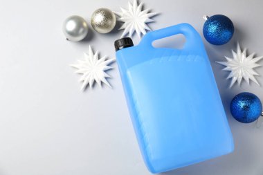 Plastik şişede antifriz, takılar ve gri arka planda dekoratif kar taneleri. Metin için boşluk