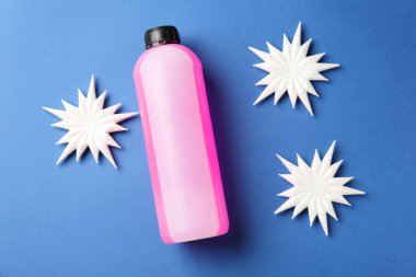 Plastik şişede antifriz ve mavi arka planda dekoratif kar taneleri.