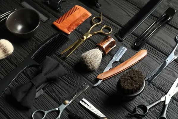 Siyah ahşap masanın üzerinde birçok farklı berber aletleri var.