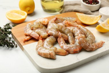 Beyaz masada taze çiğ karides, baharat ve limon, yakın plan.