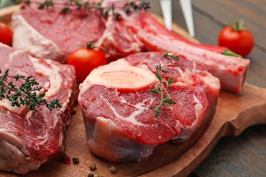 Çiğ et parçaları, domates ve baharatlar ahşap masada, yakın plan.