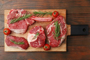 Tahta masada çiğ et, biberiye ve domates parçaları.