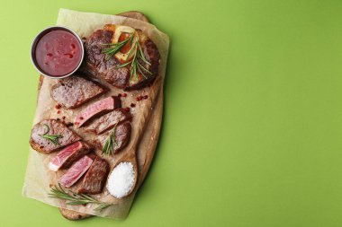 Lezzetli et parçaları, baharatlar ve soslar yeşil arka planda, üst manzara. Metin için boşluk