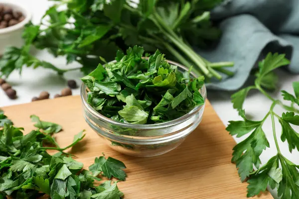 Fresh parsley in bowl on white table, closeup