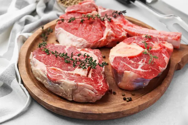 Açık gri masada çiğ et ve baharat parçaları, yakın plan.