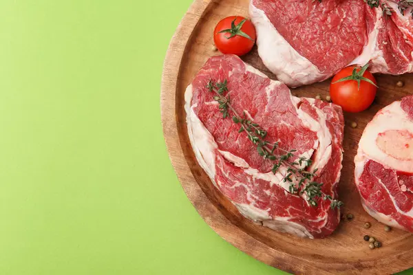 Çiğ et parçaları, baharatlar ve domatesler yeşil masada, üst tarafta. Metin için boşluk