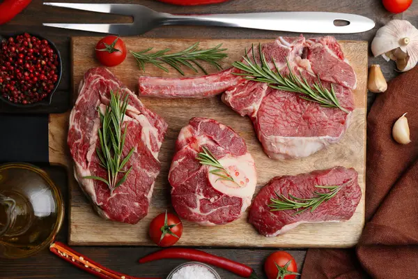 Çiğ et parçaları, baharatlar ve ürünler ahşap masa üzerinde, düz yatıyordu.