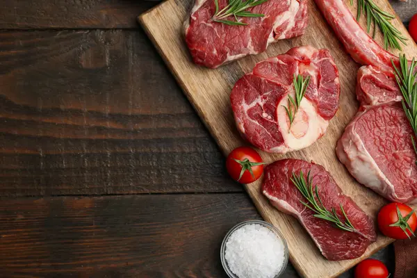 Çiğ et, biberiye, ahşap masada tuz ve domates parçaları. Metin için boşluk