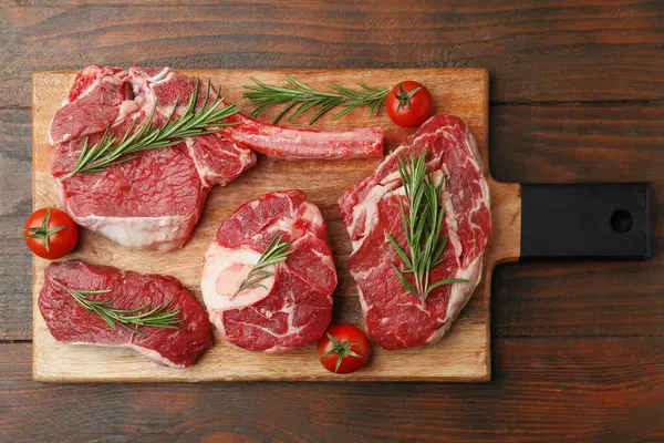 Tahta masada çiğ et, biberiye ve domates parçaları.