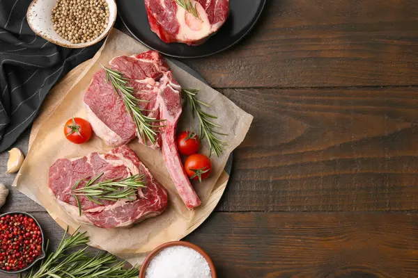 Çiğ et parçaları, domates ve baharatlar ahşap masada, düz yerde. Metin için boşluk