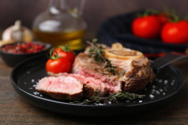 Lezzetli et parçaları, ahşap masada baharatlar ve domatesler, yakın plan.