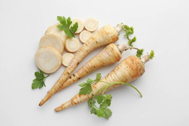 Parsley roots and leaves on white background, flat lay